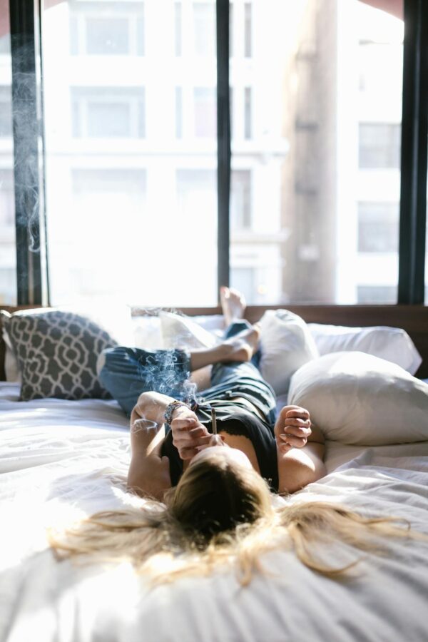 A Woman Lying on the Bed while Smoking Weed